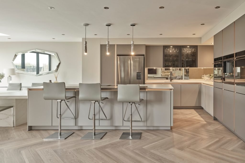A modern cool, grey kitchen with a kitchen island and bar stools